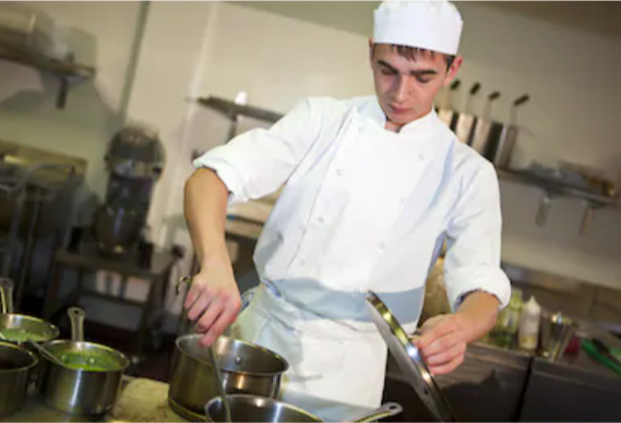 Young person in chef whites cooking in a kitchen