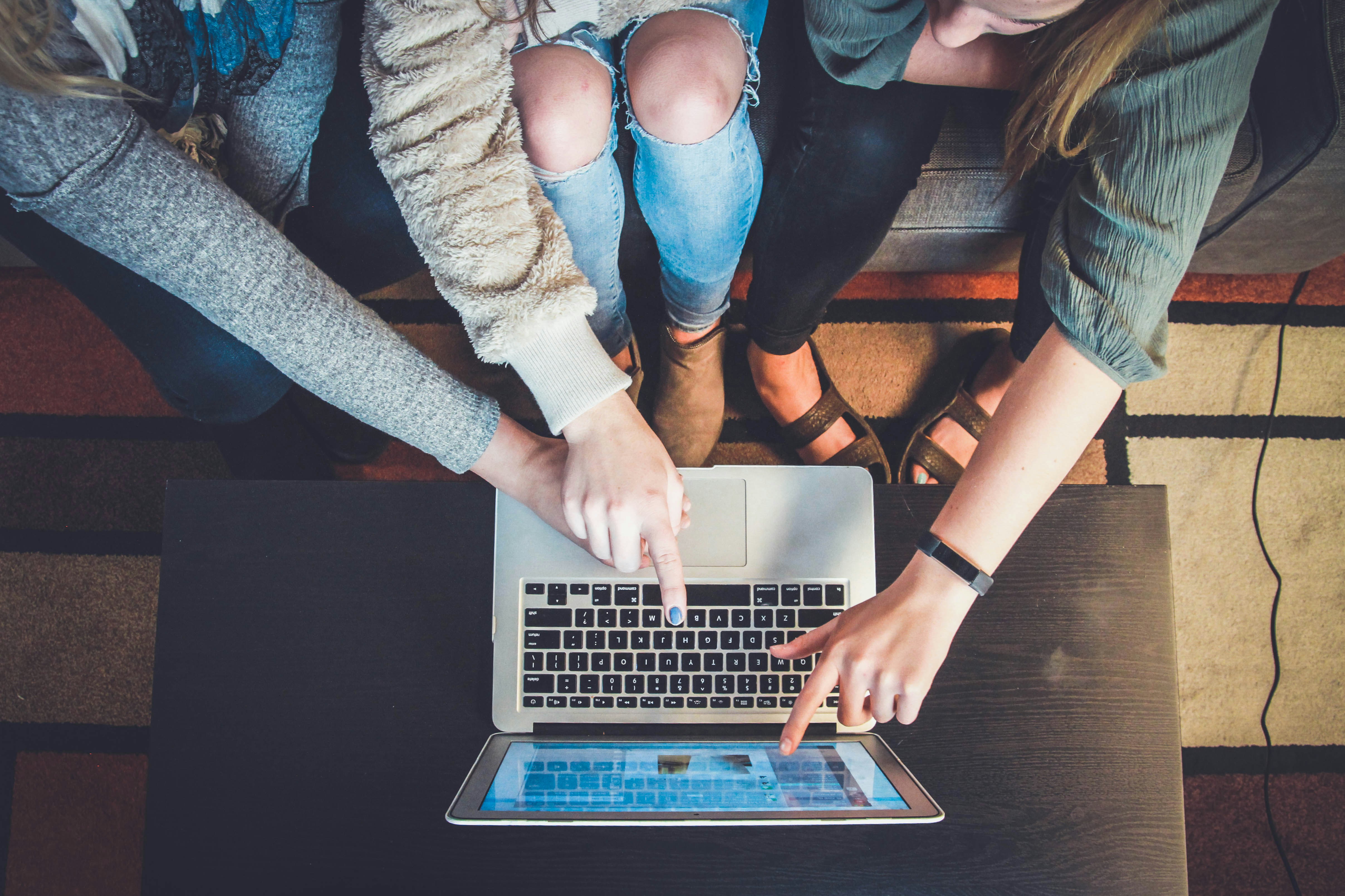 Three people pointing at a laptop screen, collaborating on a project.